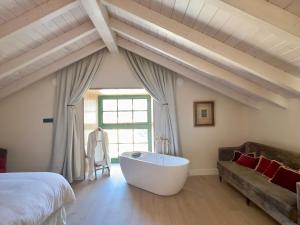 a bedroom with a bed and a bath tub and a couch at La Casa de las Flores in Noceda del Bierzo