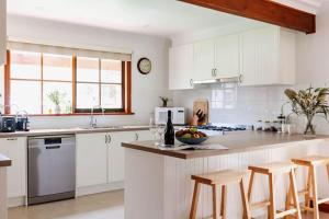 a kitchen with white cabinets and a bowl of fruit on a counter at The Cottage at Paramoor Winery in Carlsruhe