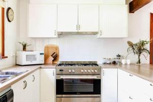 a kitchen with white cabinets and a stove top oven at The Cottage at Paramoor Winery in Carlsruhe