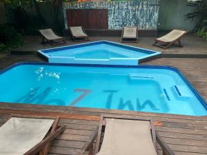 a large swimming pool with two chairs and a table at Moz Inn - Coconut View Resort in Lopes