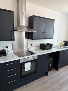 a kitchen with black cabinets and a stove top oven at Broadway residence G01 in Bradford