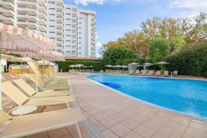 a swimming pool with lounge chairs and umbrellas at SOL by Meliá Guadalupe in Magaluf