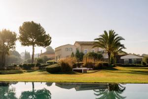 a house with palm trees and a pool of water at Fontsanta Hotel Thermal & Spa - Adults Only in Colònia de Sant Jordi