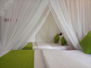 a bedroom with two beds with white curtains and green pillows at Golden View Guest Ella in Ella