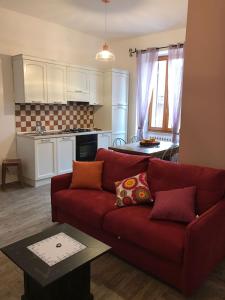 a living room with a red couch and a kitchen at Appartamento con terrazza in Via Campo dei Fiori in Spoleto