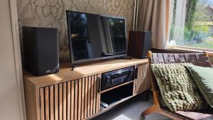 a television on a wooden entertainment center with two speakers at Huisje Piet in Hoenderloo