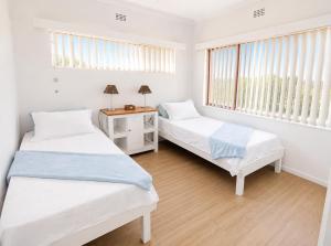 two beds in a room with two windows at Die Ou Lady - Dwarskersbos in Velddrif