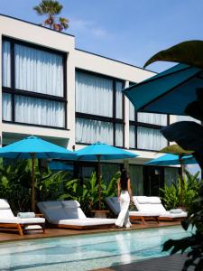 a woman walking by a pool in front of a building at Awwa Boutique Hotel in Canggu