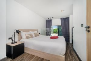 a bedroom with a white bed with a red pillow on it at Relax, Swim & Stay Active in this Duplex - UTL B131 in Rawai Beach +13 photos