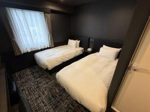 a hotel room with two beds and a window at HOTEL KAN-RAKU Mishima Main Street in Mishima