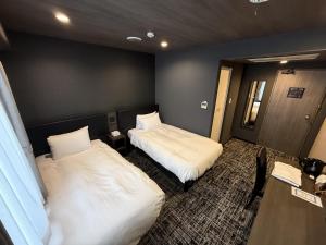 a hotel room with two beds and a table at HOTEL KAN-RAKU Mishima Main Street in Mishima