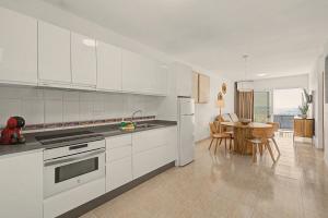 a kitchen with white cabinets and a dining room with a table at Callao Beach 2 in Arrieta