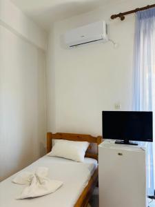 a bedroom with a bed with a tv and a refrigerator at Summer Rooms in Skala Kallirachis