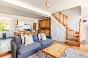 a living room with a blue couch and a kitchen at 2a Coastguard Cottages in Gorran Haven