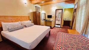 a bedroom with a large white bed and a desk at Aranyasun Masinagudi - Formerly known as Tamarind Tree in Masinagudi