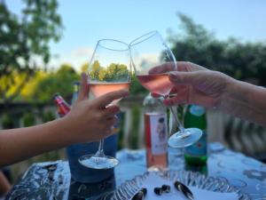 two people holding up glasses of wine at a table at Kiki - Emerald River Suite with Private Gardens in Čapljina