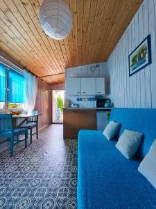 a bedroom with a blue bed and a kitchen at OliMarii domki nad jeziorem Jezioro Złotnickie Karłowice 19 a,b in Karłowice