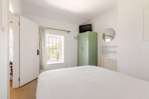 a bedroom with a white bed and a green cabinet at 2a Coastguard Cottages in Gorran Haven