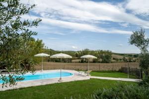 a swimming pool with two umbrellas in a yard at Rifugio Vita Luminosa in Montecarotto