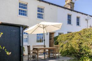 a table with an umbrella in front of a house at 2a Coastguard Cottages in Gorran Haven