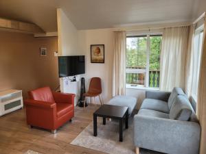a living room with a couch and a chair at Thingvellir Lake Cottage in Veiðilundur