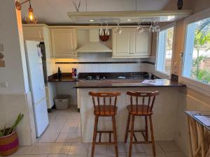a kitchen with two bar stools at a counter at Bungalow Les Coraux in La Saline les Bains +22 photos