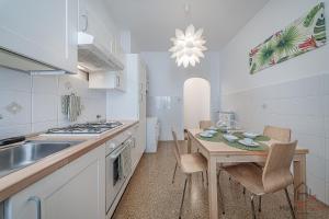a kitchen with a table and a sink and a stove at Gramsci House - Sea 3 min - Central - Family in Vado Ligure