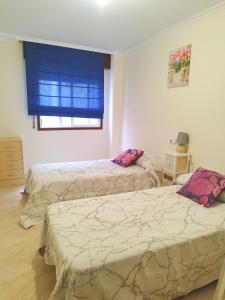a bedroom with two beds and a window at VIVIENDA TURÍSTICA Bajo, 7 Escaleras in Laxe