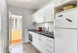 a white kitchen with a sink and a refrigerator at Escala Riells in L'Escala +17 photos