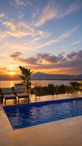 a swimming pool with a sunset in the background at Vatër by the lake in Shirokë