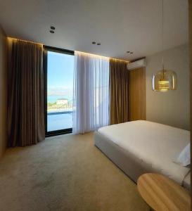 a bedroom with a large bed and a large window at Vatër by the lake in Shirokë
