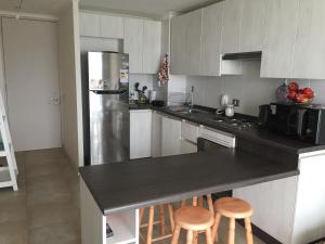 una cocina con nevera de acero inoxidable y taburetes en Los Perales Poniente Apartment, en La Serena