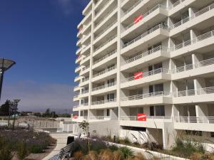 un gran edificio de apartamentos blanco con balcones y flores en Los Perales Poniente Apartment, en La Serena