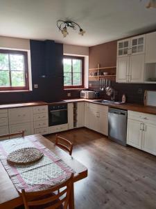 a kitchen with white cabinets and a table and a table and chairs at Penzion Farma Dolík in Havlíčkŭv Brod