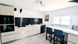 a kitchen with white cabinets and black tiles on the wall at Tranquillity in a modern unit in Bazugues