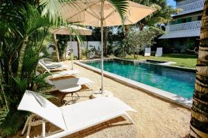 a pool with white lounge chairs and an umbrella at Le Mandala Moris Boutique Hotel in Grand-Baie