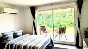 a bedroom with a bed and a balcony with chairs at Tranquillity in a modern unit in Bazugues