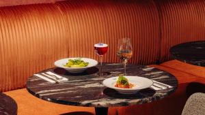 a table with two plates of food and a glass of wine at NYX Hotel Amsterdam Rembrandt Square in Amsterdam +29 photos