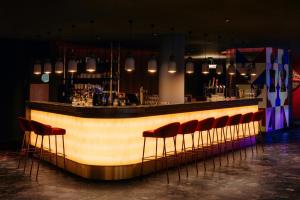 a bar with a row of red bar stools at NYX Hotel Amsterdam Rembrandt Square in Amsterdam