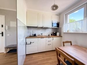 a kitchen with white cabinets and a table and a window at Apartament Biłgorajski przy Rynku in Biłgoraj +11 photos