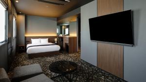 a hotel room with a bed and a flat screen tv at HOTEL SUI HAMAMATSU by ABEST in Hamamatsu