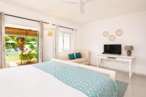 a white bedroom with a bed and a television at Le Mandala Moris Boutique Hotel in Grand-Baie