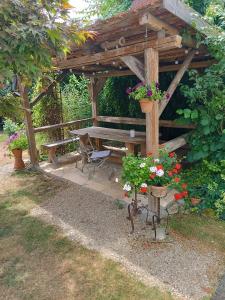 a wooden pergola with a picnic table and flowers at Studio im Krater in Wallerstein +3 photos