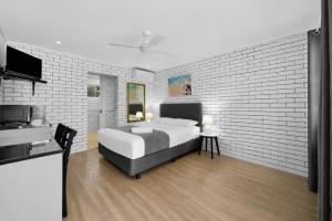 a bedroom with a bed and a white brick wall at Pacific Paradise Airport Motel in Pacific Paradise 