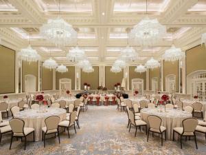 a banquet hall with tables and chairs and chandeliers at Raffles Singapore in Singapore