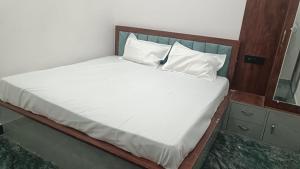a bed with white sheets and pillows in a room at Hotel Kunj Palace in Etah