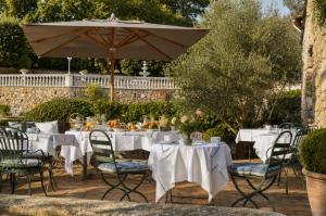 a table with white tables and an umbrella at Les Rosées in Mougins