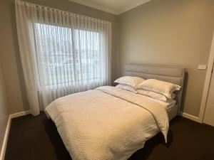 a bedroom with a bed with white sheets and a window at Central 3BR Home in Mansfield