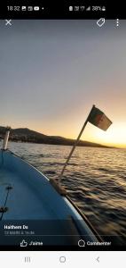 a boat with a flag in the water at Marina in Tipaza