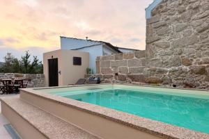 a swimming pool in front of a stone building at Casa do Largo do Cruzeiro in Vouzela